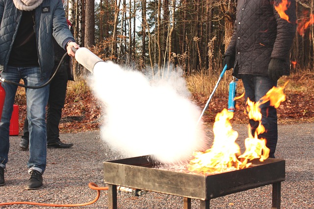 Personas extinguiendo un fuego con un extintor durante un simulacro de incendio al aire libre, demostrando prácticas de seguridad contra incendios.